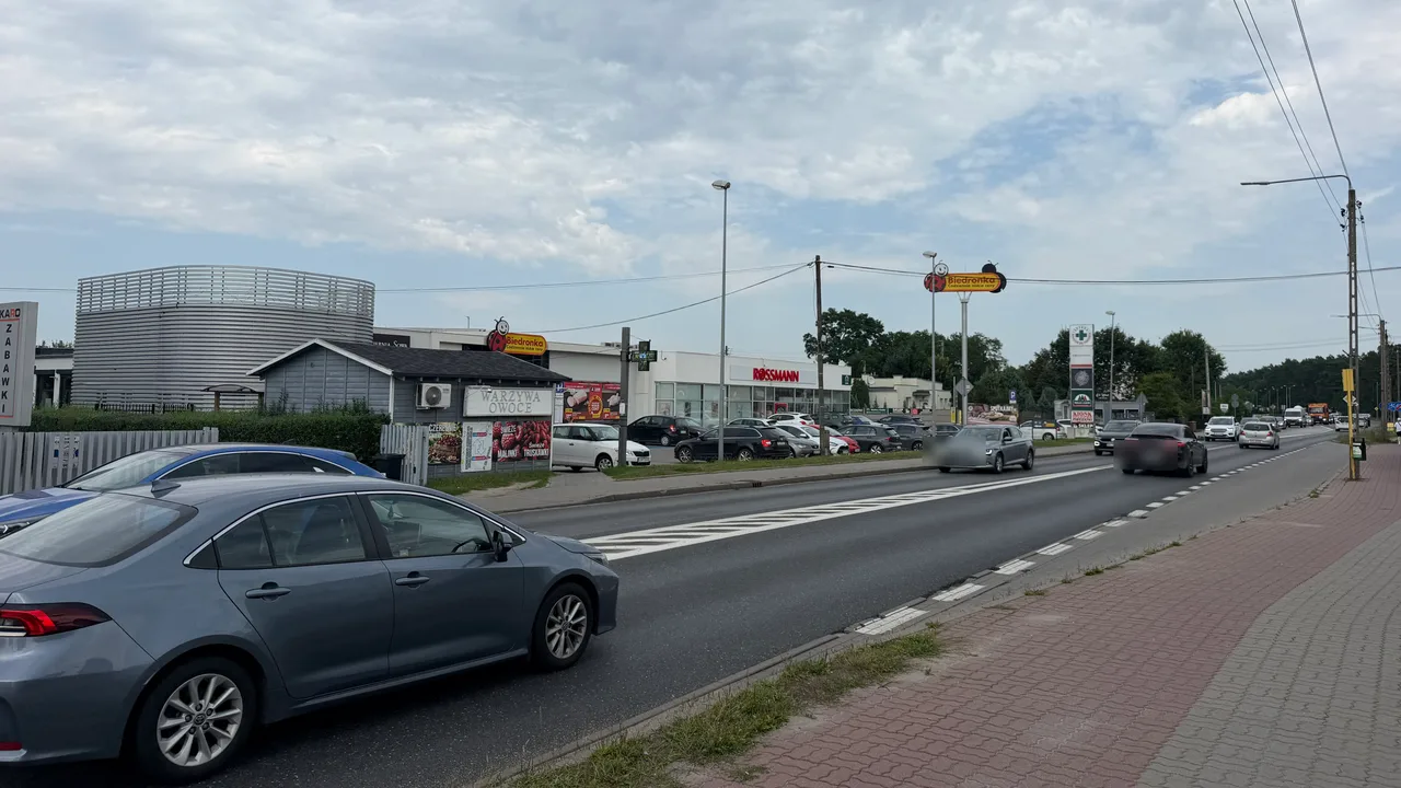 Droga wojewódzka 223 przez Białe Błota — dwa pasy ruchu, przejście dla pieszych i zjazdy na parkingi przy pasie handlowym